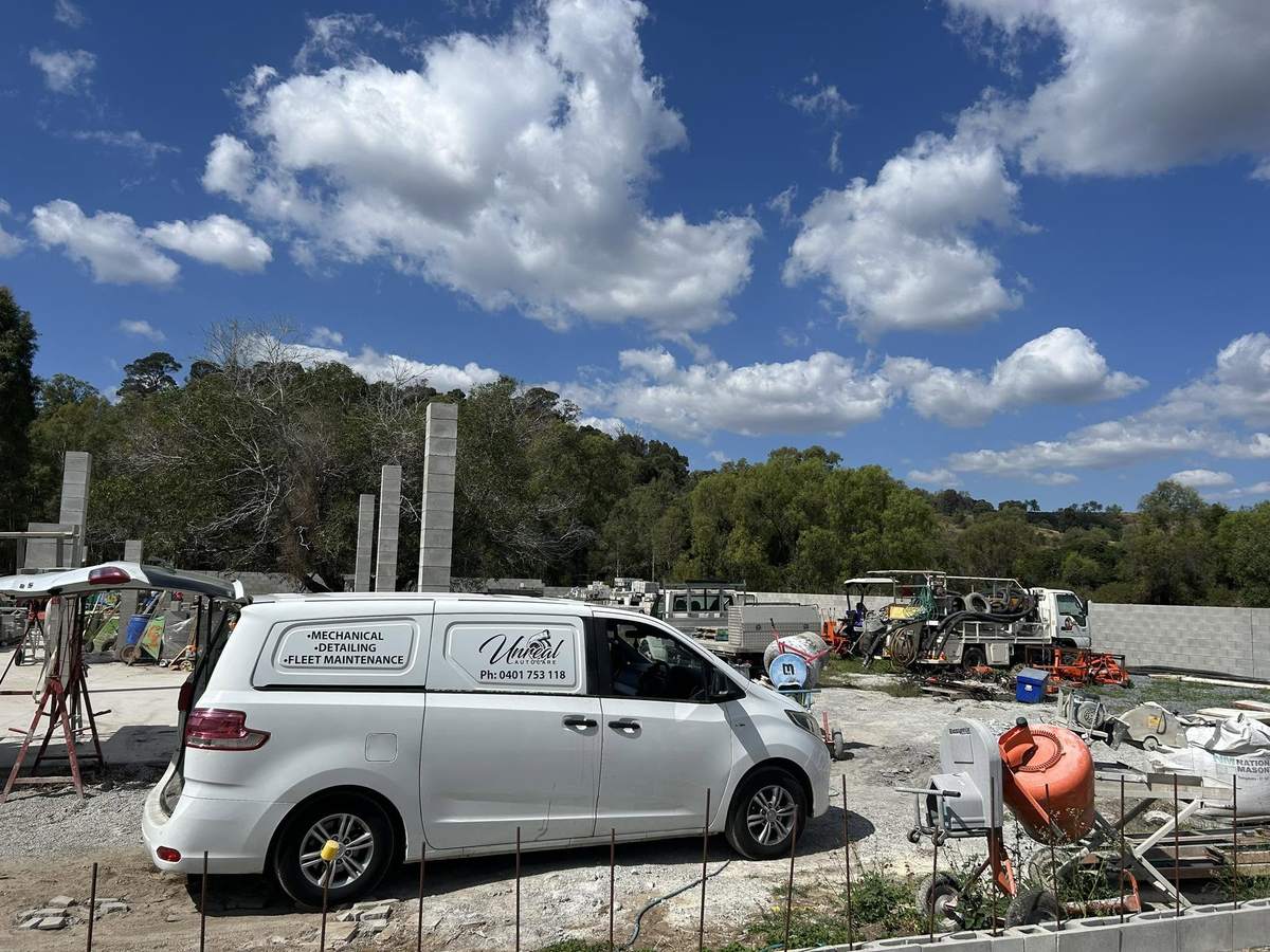 Unreal Auto Care van parked at a building site